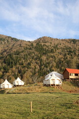 View of glamping tent on the nature in the beautiful countryside in the mountains in summer. White tent glamping camp. Luxury campsite.
