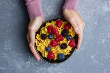 Corn flakes with berries in black bowl