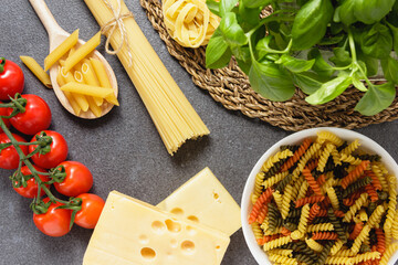Raw fusilli in bowl on grey background.