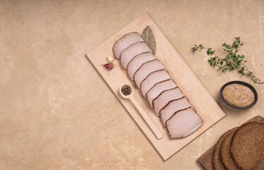 Smoked pork cut into thin slices. Serving on a wooden board on a beige background