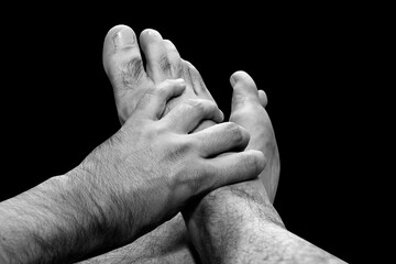 Fototapeta premium Male hand holding male feet