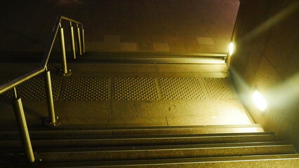Grand plan d'escalier éclairé par des projecteurs de lumière blanche ou jaune, vide,...