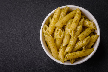 Delicious fresh pasta penne with green pesto sauce with basil, salt and spices