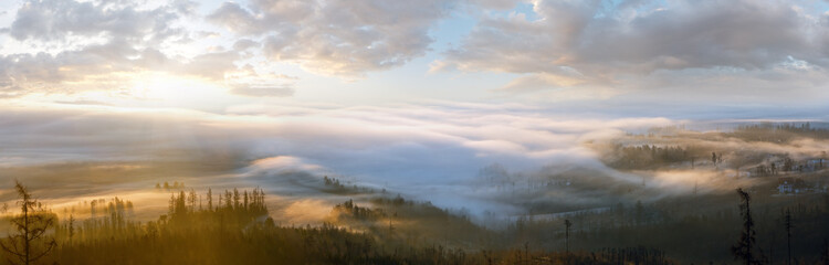 Clouds illuminated by the morning sun floating low over the valley. Country panorama.
