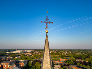 Captured from an aerial perspective, this image features the spire of a church with an ornate cross...