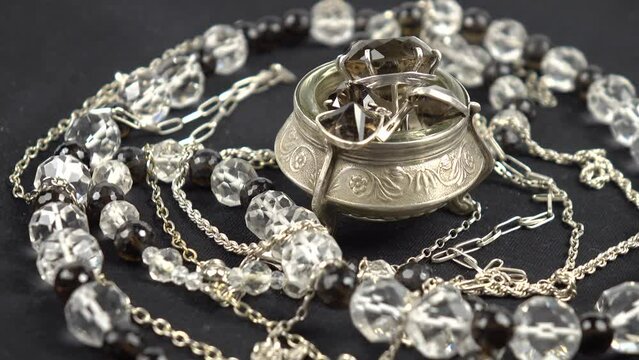 Silver rings with smoky topaz in a silver jewelry box and the vintage beads made of cut rock crystal and smoky topaz are placed on a black cloth. Inheritance, family collection