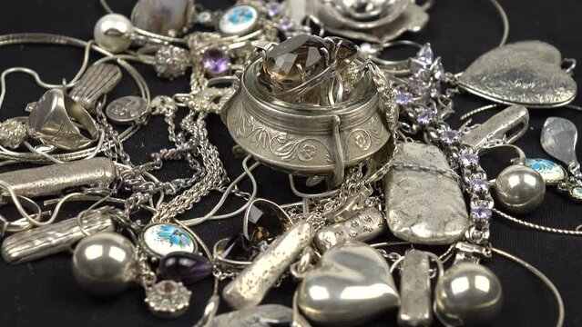 Silver rings with smoky topaz in a silver jewelry box and the vintage silver jewelries of various forms and functions are placed on a black cloth. Inheritance, family collection