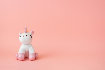 A toy unicorn on a pink background. Copy space