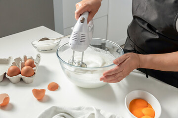 A female hands beat egg whites with a mixer