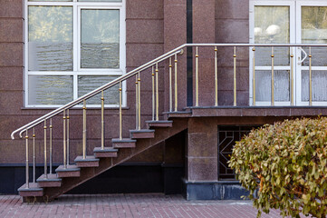 Threshold with steps with an iron fence of twigs. Marble wall with windows and entrance to the office