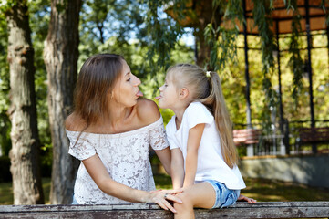 Mother and daughter walk in the summer city park. Childhood, leisure and people concept - happy...