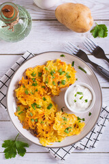 Traditional potato latkes with greens and sauce on a plate on the table top and vertical view