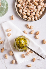 Fototapeta na wymiar Jar with pistachio cream butter and pistachios on the table top and vertical view