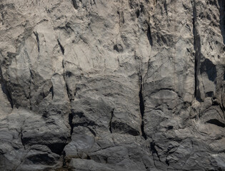 Weathered seaside rock face texture . Aged volcanic stone wall surface background pattern with cracks and scratches. Ischia Island, Italy.