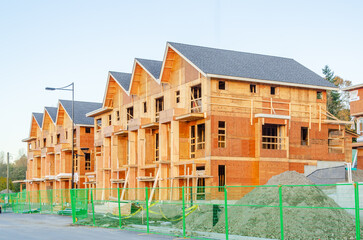 Low-rise building under construction. The site with cranes against blue sky