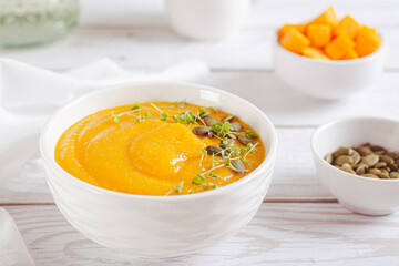 Homemade pumpkin polenta with seeds and microgreens in a bowl on the table