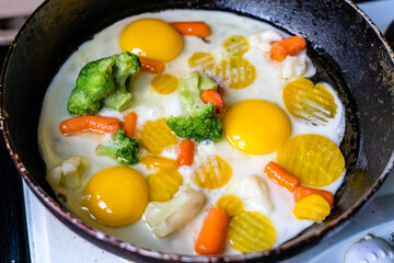 Composition with fried eggs and vegetables in a pan