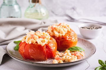 Baked tomato halves filled with scrambled egg and basil on a plate on the table