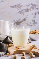 Lactose-free pistachio milk in a glass and nuts on the table vertical view