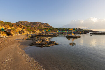 A beautiful, romantic beach illuminated by the morning rays of the sun. In the sea, there are...