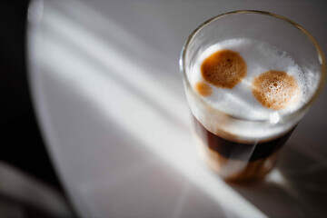 cappuccino in a glass glass on the table under the rays of the sun