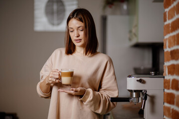 beautiful woman with a cup of cappuccino at the coffee machine, coffee making concept