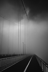 Forth Road Bridge covered in thick fog in the early morning in black and white. Scotland, United...