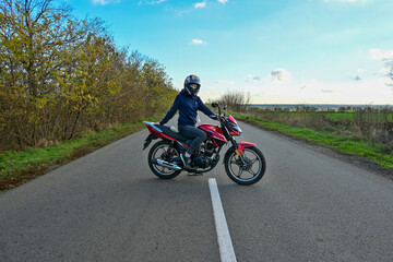 Fototapeta na wymiar biker girl in a helmet sits on a motorcycle on the road.