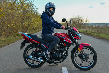 Fototapeta na wymiar biker girl in a helmet sits on a motorcycle on the road.