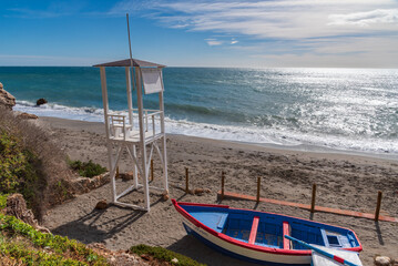 Watchtower and small decorative boat on Carabeo beach in the municipality of Nerja, Malaga.