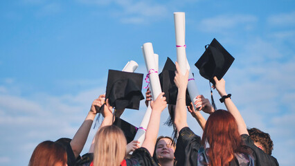 College graduates raise their caps and diplomas upward.
