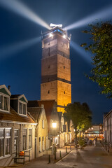 Fototapeta premium Lighthouse Brandaris at Terschelling with historic street and bright light beam