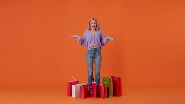 Attractive woman counting colorful shopping bags in studio