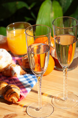 romantic breakfast for two on the terrace in the morning sun, champagne, juice, pastries and fruits, healthy, healthy, vertical.