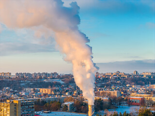 Aerial drone view of pollution in a city. White smoke coming from an industrial chimney located in...