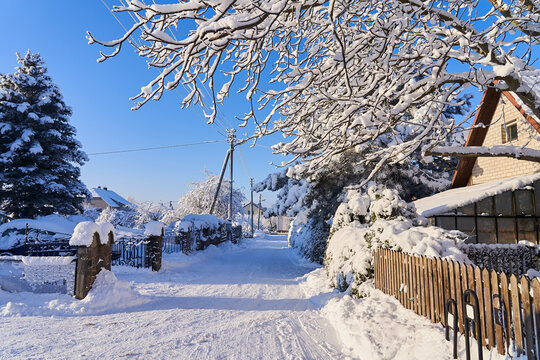 Snow-covered houses in the village in winter. Clearing yards of snow