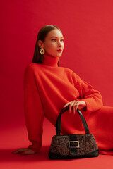 Fashionable confident woman wearing trendy red knitted turtleneck dress, big golden earrings,...