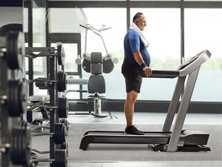 Fototapeta na wymiar Mature man standing on a treadmill at the gym