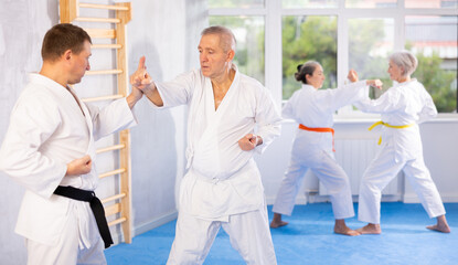 Dynamic photo capturing energy and focus of senior athletics students people fighting in karate class. Obtaining black belt, advanced training, highest dan of martial arts. Sport to max.