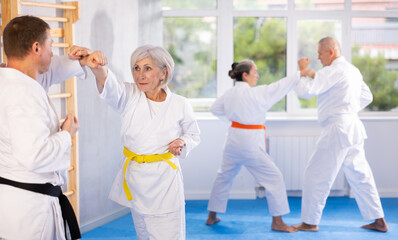 Senior karate practitioner engage in fierce fight, perseverance during martial arts discipline,...