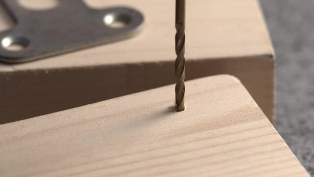 Carpenter drills board with a thin drill, close-up