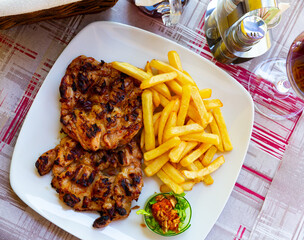 Grilled boneless chicken thighs (Pileci Batak) served with fries and sauce on white plate. Traditional Balkan cuisine