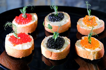 Partitioned dish with black and red caviar on wooden background