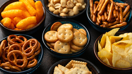Salty snacks crackers, potato chips, pretzel, peanuts, corn puffs. - obrazy, fototapety, plakaty