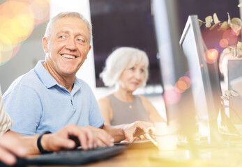 Old-aged male student learning computer programs with interest in training room