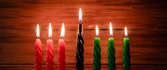 Happy Kwanzaa. African American holiday. Seven burning candles, red, black and green, in kinara...