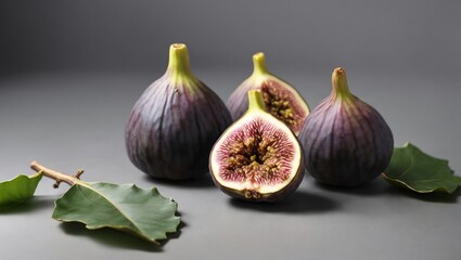 Figs with some cut showing the inside and leaves on a well-lit gray background