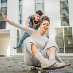 Young man and woman teenager couple have fun by the modern building