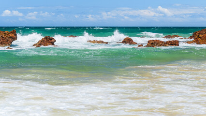 Australian coast with volcanic rocks on the shore, view from the beach to the horizon with blue...