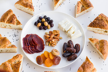 Traditional Turkish Ramadan,Iftar Start Menu Plate with dry aged meat,bacon,fruits and sliced Ramadan Bread on white surface